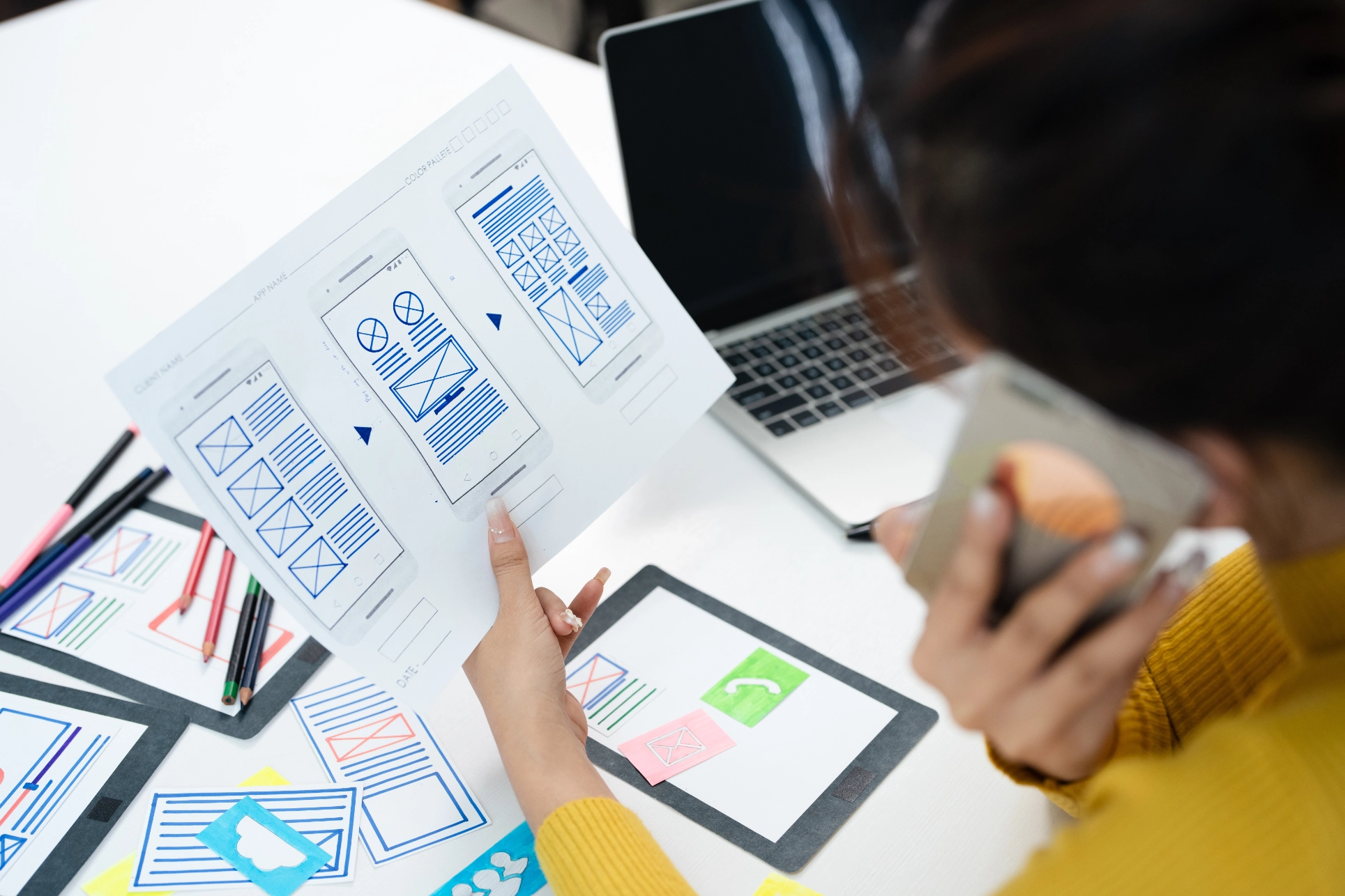 Woman looking at website wireframe whilst taking a phone call.